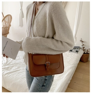 Close-up of a brown vintage PU leather crossbody bag with metallic buckle detail