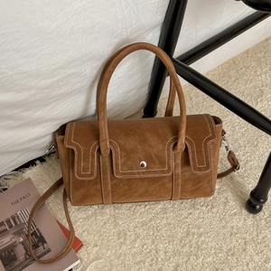 Sac à main vintage marron en daim avec grande capacité sur un tapis blanc doux