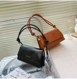 Close-up of black and brown leather crossbody flap bags with gold knot hardware detail