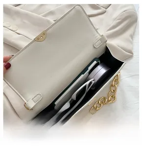 Capacità interna della borsa trapuntata color crema con oggetti quotidiani e catena oro