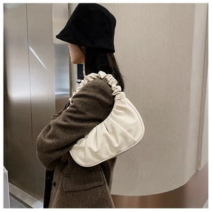 Détail d'un sac baguette plissé beige avec plis en nuage et poignée froncée élégante