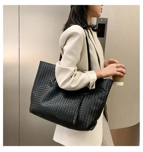 Close-up of black woven tote bag showing luxury leather texture on a woman's shoulder