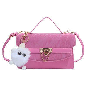 Pink crossbody square bag with gold lock, top handle and plush charm on white background