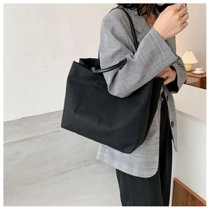 Minimalist large canvas tote bag with slim shoulder straps shown on a stylish model
