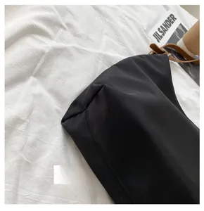 Detail view of the black fabric tote bag base with leather strap and silver buckle