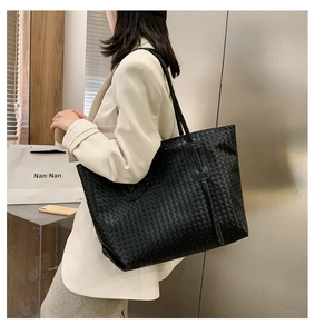 Detail view of large black woven tote bag made of high-quality leather for street style