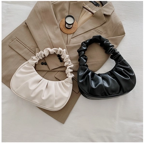Détails des sacs demi-lune plissés en noir et crème sur un tissu doux