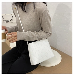 Détail du sac bandoulière blanc matelassé à losanges avec coutures fines porté par un mannequin
