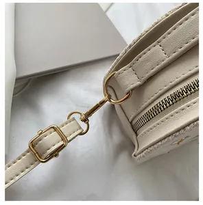 Gros plan du sac beige clair avec broderie de marguerites et crochets en métal doré
