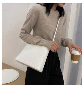 Détail d'un sac seau en cuir matelassé blanc avec des finitions dorées chic