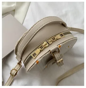 Détail de la double fermeture éclair dorée de haute qualité sur le sac bandoulière rond beige