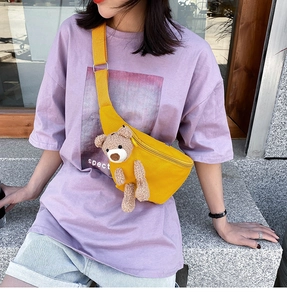 Macro shot of bright yellow canvas chest bag with 3D brown plush bear and adjustable strap