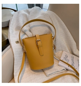 Detail of a bright yellow bucket bag with decorative strap and adjustable shoulder strap