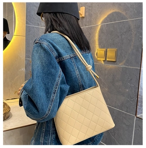 Détail d'un sac seau crème matelassé avec une bandoulière à nœud distinctive