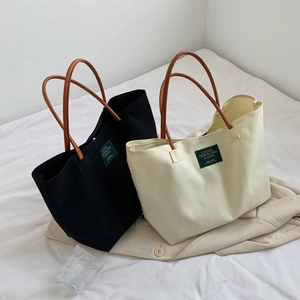 Minimalist canvas tote bags in black and cream with premium leather handles and woven labels
