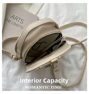 Vue détaillée des deux compartiments zippés et de l'intérieur du sac rond tissé ivoire