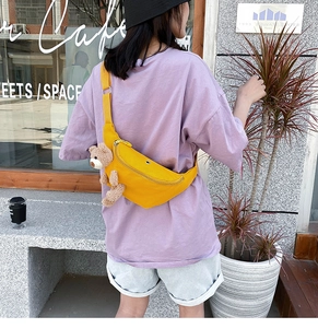 Detail of yellow canvas waist bag with cute teddy bear charm and adjustable strap