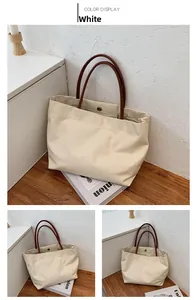 Detail of canvas tote bag showing the metal snap button closure and brown leather straps