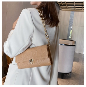 Dettaglio borsa trapuntata kaki con catena dorata su un blazer bianco
