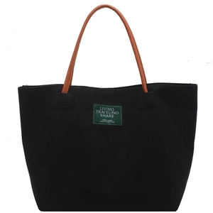 Minimalist canvas tote bag in black with brown straps and green label, spacious shoulder bag