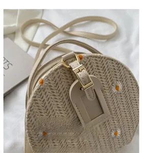 Détails de la sacoche ronde beige tissée avec des motifs de marguerites brodés élégants