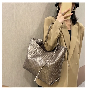Detail of champagne gold woven tote bag with Intrecciato pattern on a female model