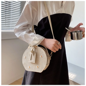 Gros plan du sac en paille rond avec broderie marguerite et détail de fermeture éclair dorée