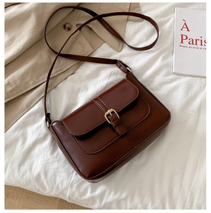 Detail of a chocolate brown vintage crossbody bag with a metal buckle and PU leather texture