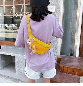 Outdoor shot showing the adjustable strap and cute bear charm on this yellow canvas bag