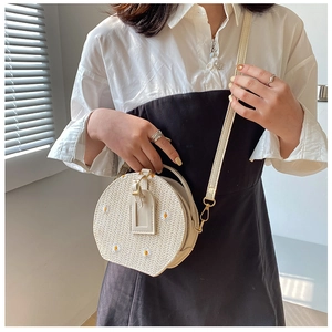 Détail d'un sac rond tressé avec broderie de marguerites et bandoulière réglable