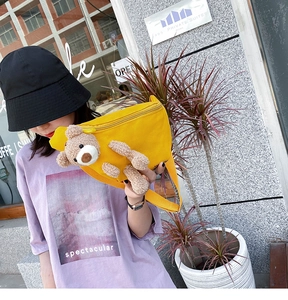 Detail of yellow canvas crossbody bag featuring a 3D plush bear and adjustable strap