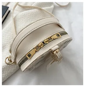 Detail of smooth gold zipper and floral embroidery on cream woven crossbody bag