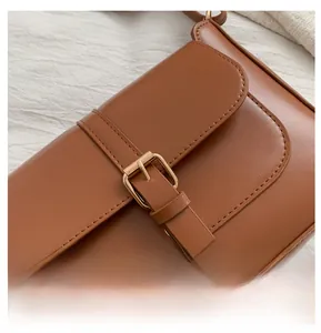 Close-up of caramel PU leather flap bag with fine stitching and metal pin buckle