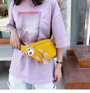 Detail of yellow canvas waist bag featuring a cute 3D teddy bear doll and zipper closure