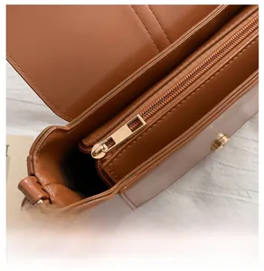 Detail of smooth gold metal zipper and magnetic closure on cognac PU leather crossbody bag
