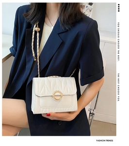 Détail du sac bandoulière blanc matelassé avec boucle en perles et chaîne dorée sur veste