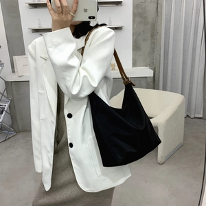 Minimalist black tote bag with brown leather shoulder strap in a stylish casual outfit