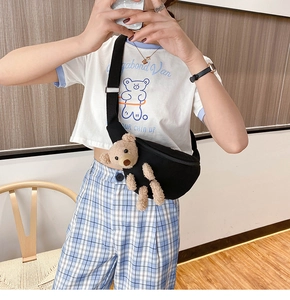 Close-up of a black canvas crossbody chest bag featuring a 3D plush bear ornament