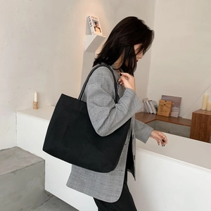 Minimalist large black canvas tote bag with slim shoulder straps for daily commuting
