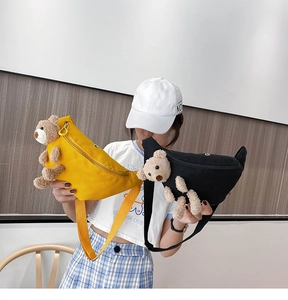 Detail of yellow and black canvas waist bags featuring a 3D teddy bear plush decoration