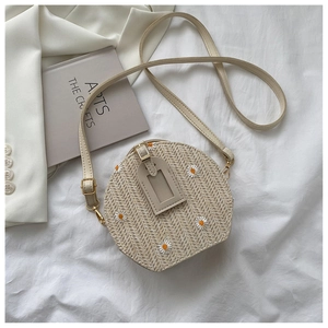 Détail du sac bandoulière en paille tressée avec broderie marguerite et lanière cuir