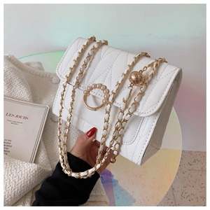 Détail du sac à bandoulière matelassé blanc avec chaîne dorée et boucle perle