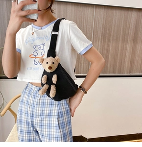 Close-up of black canvas chest bag with a cute plush bear decoration and nylon strap