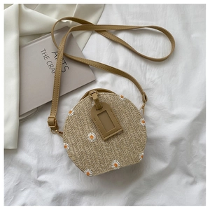 Détail du sac bandoulière rond en paille avec broderie marguerite et lanière en cuir