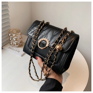 Détail du sac en similicuir noir à surpiqûres en V avec boucle perle et chaîne dorée