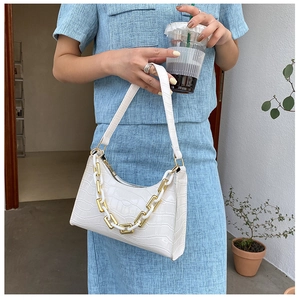 Close-up of white crocodile pattern baguette bag with stylish chunky white and gold chain
