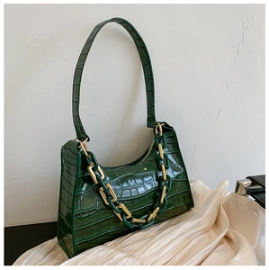 Detailed macro of crocodile pattern glossy leather baguette bag with thick chain links
