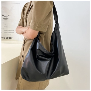 Side view of soft black faux leather hobo bag showing large capacity and knotted strap