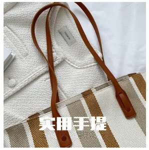 Detail showing high-capacity striped canvas tote bag with durable brown leather handles
