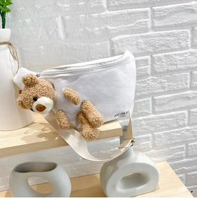 Detail of white canvas waist bag featuring a 3D plush bear and woven strap detail